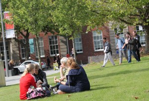Students sitting together on the grass on College Road