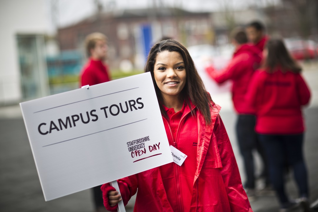 Female student ambassador holding a campus tours sign at an open day