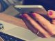 A woman's holding a phone over a laptop