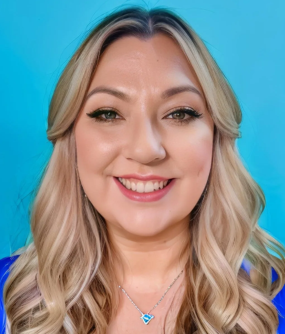 Head and shoulders shot of Jodie Heap, a smiling woman with wavy long blonde hair against a blue background.